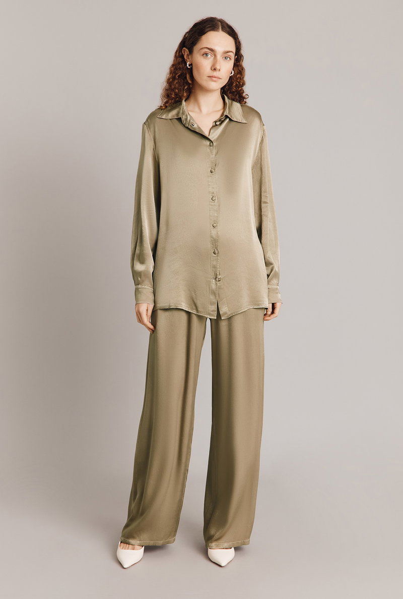 Olive satin shirt and wide-leg trousers, worn by a woman.