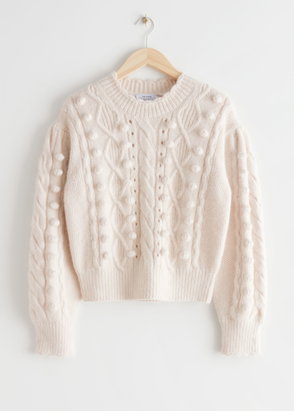 Cream cable-knit sweater with pom-pom embellishments