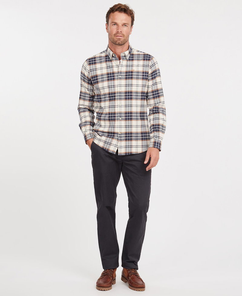Man wearing a Barbour plaid shirt and dark trousers.