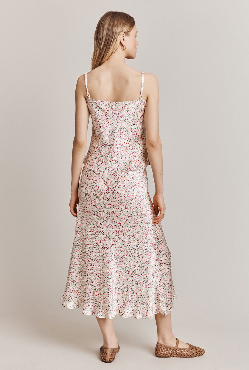 Back view of a woman wearing a floral print silk top and midi skirt.