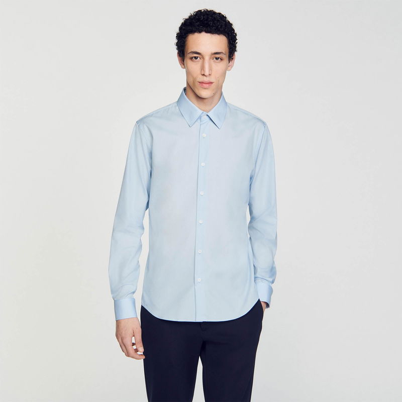 Light blue SANDRO shirt on a man, partially visible dark trousers.