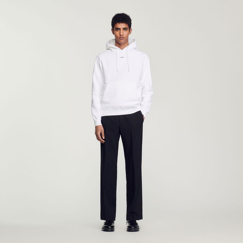 White SANDRO hoodie with black trousers and shoes.