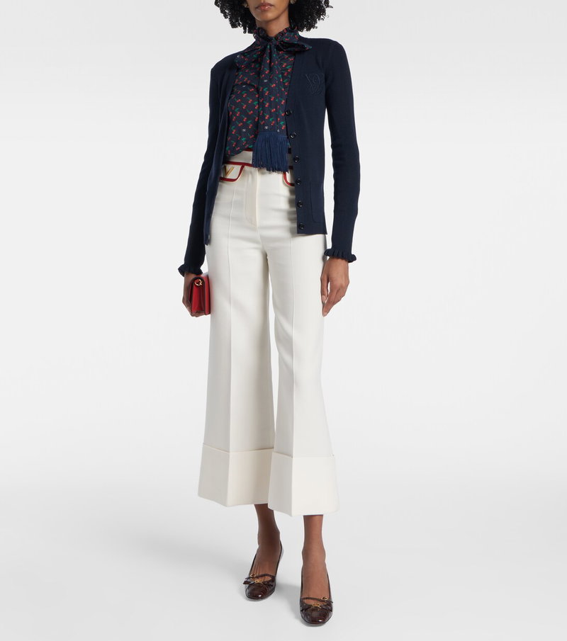 Valentino woman wearing a navy cardigan, patterned scarf, and wide-leg trousers.