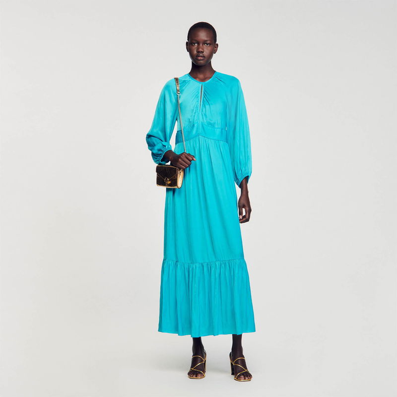 Model wearing a blue satin maxi dress with a crossbody bag