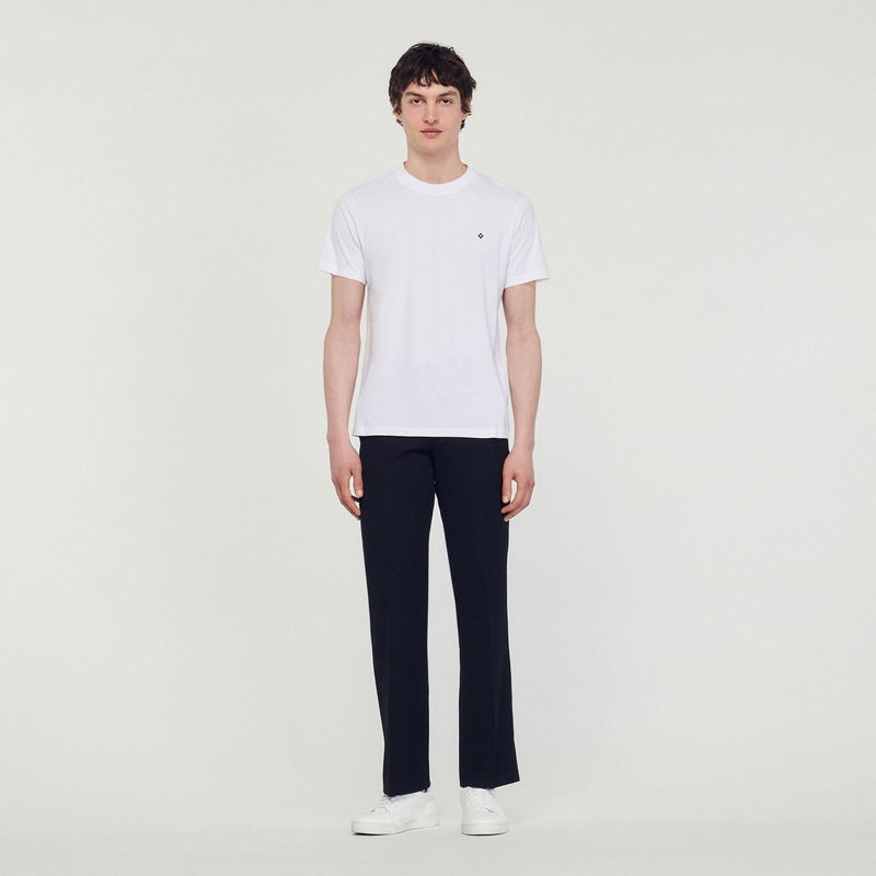Sandro man wearing a white t-shirt and black trousers.