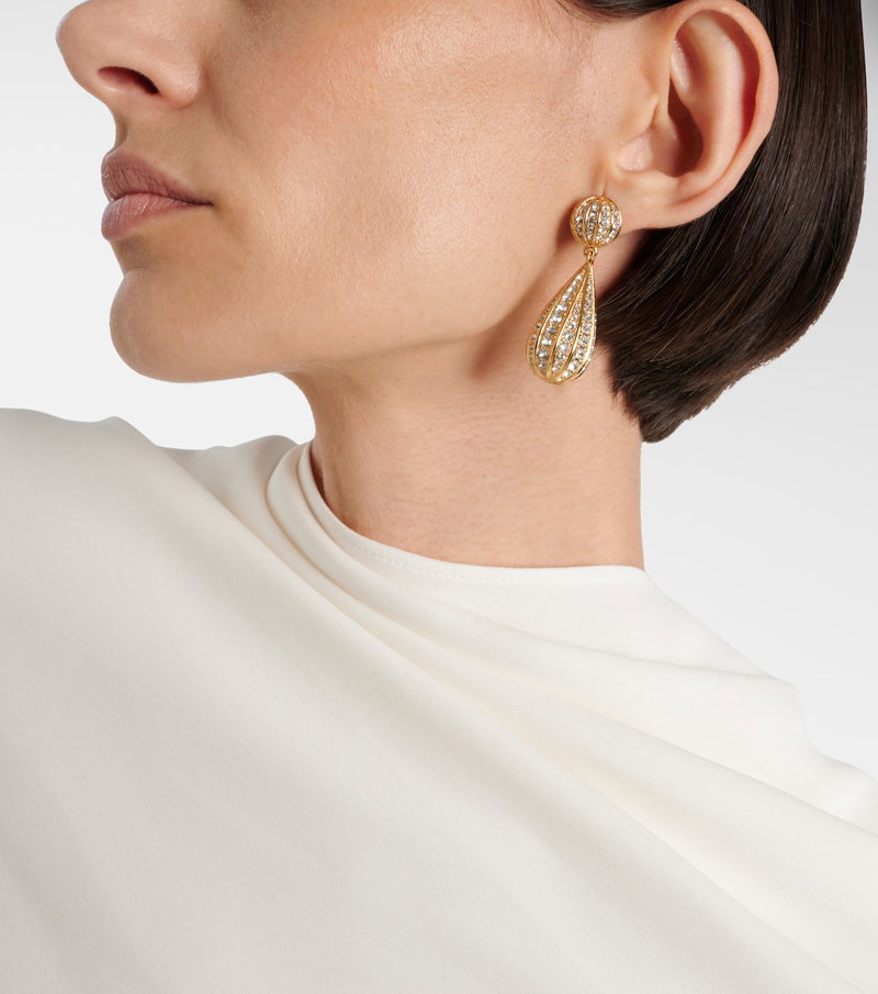 Valentino gold and crystal drop earrings on a woman's ear.