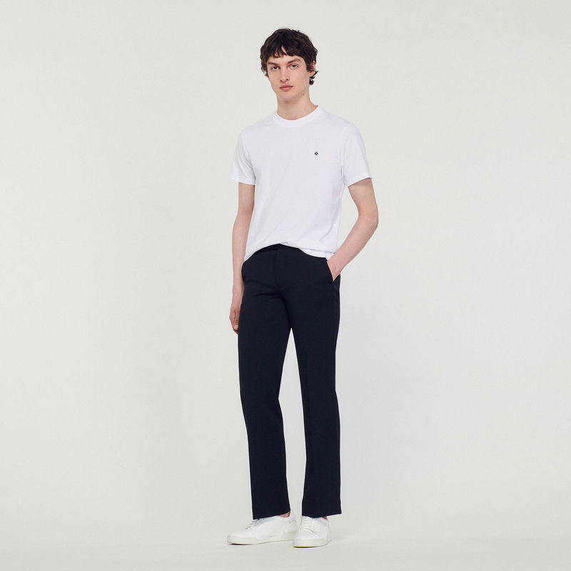 SANDRO - Young man in white t-shirt and dark trousers.