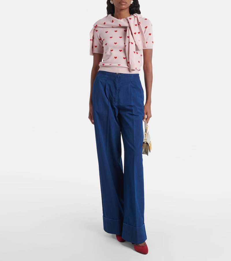 Valentino pink sweater with red embroidery, paired with blue wide-leg trousers and red heels.