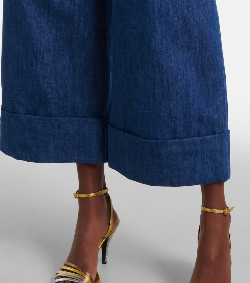 Valentino denim wide-leg trousers with gold detailing and strappy heels.