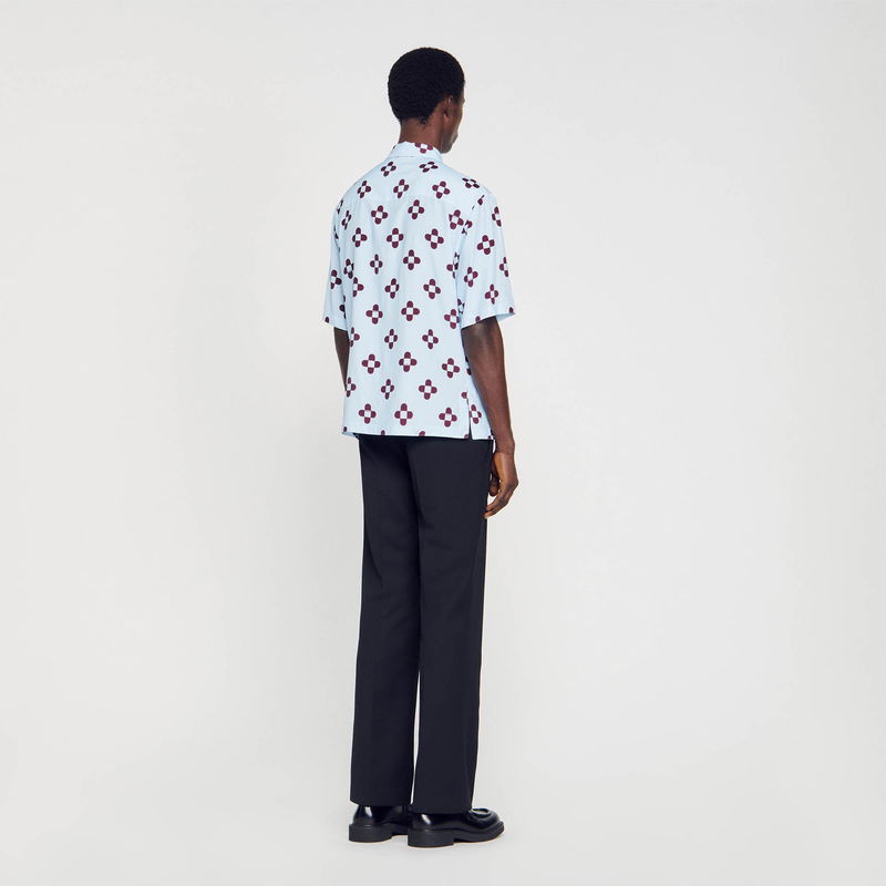 SANDRO - Man wearing a light blue shirt with maroon floral print, paired with black trousers and shoes.