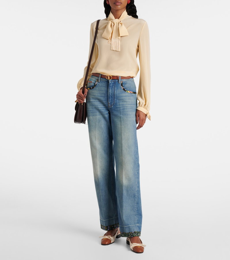 Woman wearing a yellow silk blouse with a bow and wide-leg jeans.