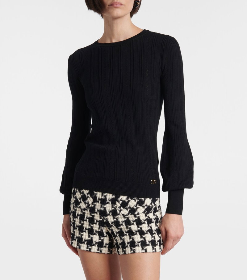 Black ribbed sweater with bell sleeves, worn by a model.