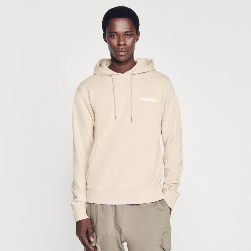 Sandro beige hoodie with logo detail, worn by a man.