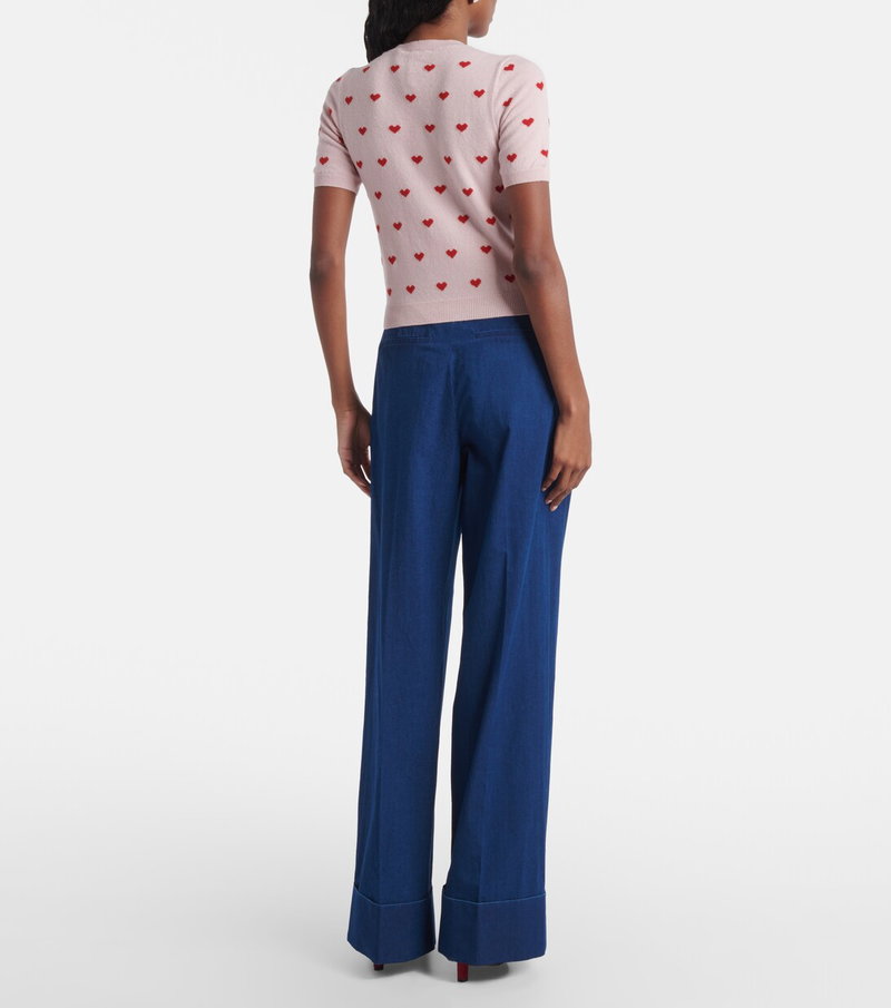 Valentino pink cardigan with heart motif, paired with wide-leg navy trousers.