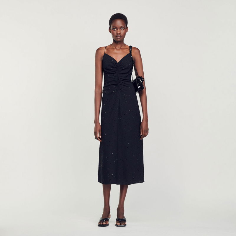 Black eyelet midi dress with chain strap and small handbag.