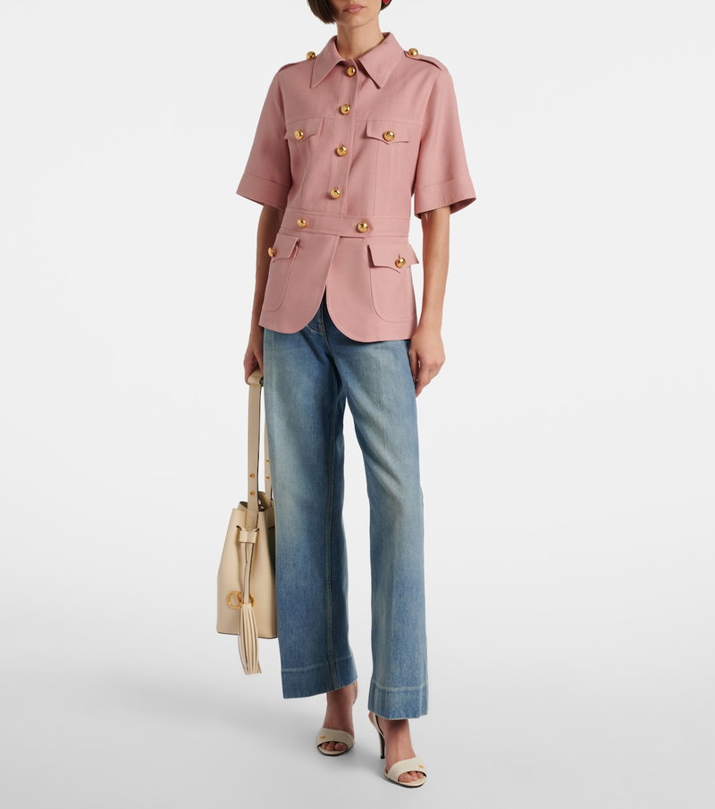 Pink cotton safari jacket with gold buttons, worn by a model with jeans and sandals.