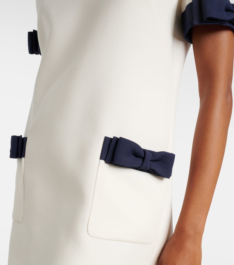 Cream sheath dress with navy bow accents and a pocket.