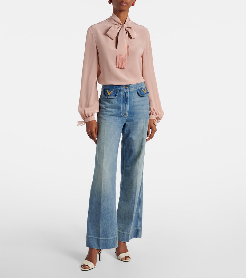 Pink Valentino blouse with a bow and fringe, paired with wide-leg jeans.