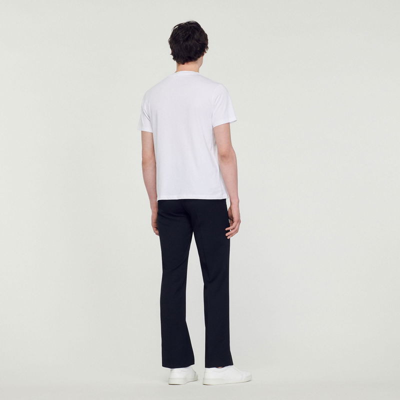 Sandro model wearing a white t-shirt and black trousers.