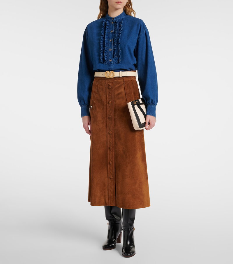 Blue denim shirt with ruffles and a brown suede skirt.