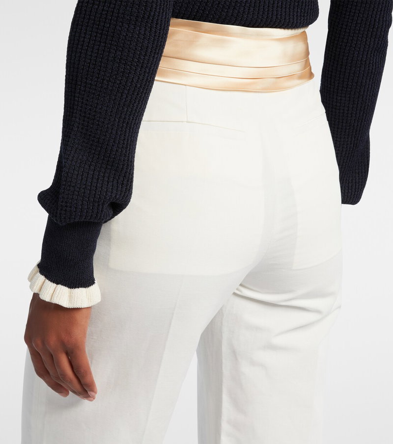 Navy ribbed sweater with gold satin belt and cream wide-leg trousers.
