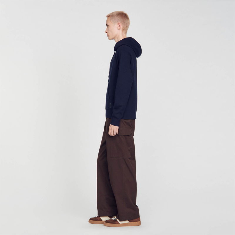 Navy hooded sweatshirt and wide-legged brown trousers on a model.