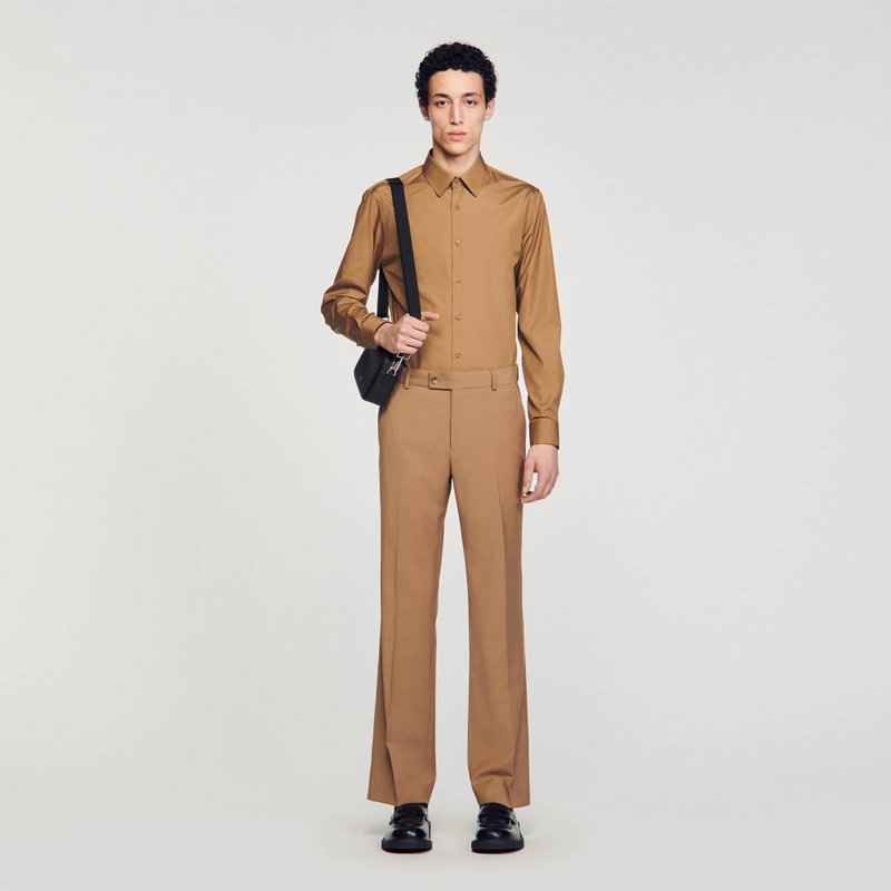 Man wearing a brown suit with a black crossbody bag