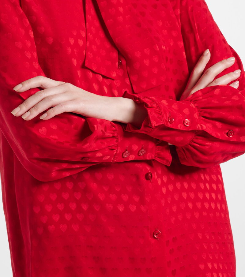 Red satin blouse with heart print, sleeves pushed up.
