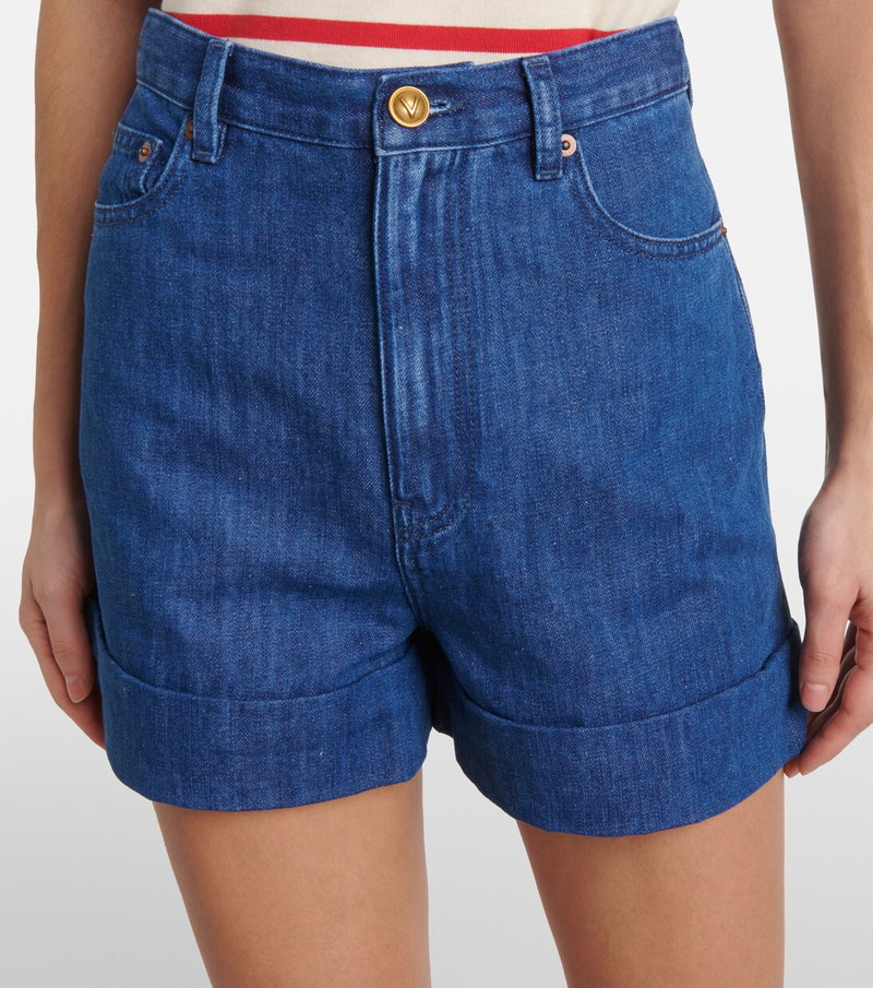 Dark-wash denim shorts with rolled-up cuffs, worn by a model.