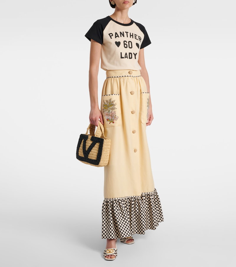 Valentino woman wearing a black and white graphic t-shirt and embroidered, button-down skirt.