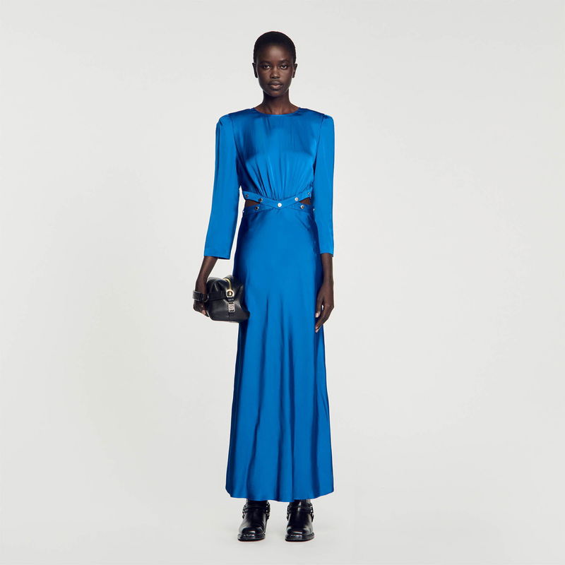 Blue satin gown with long sleeves and a belted waist, featuring a small black handbag.