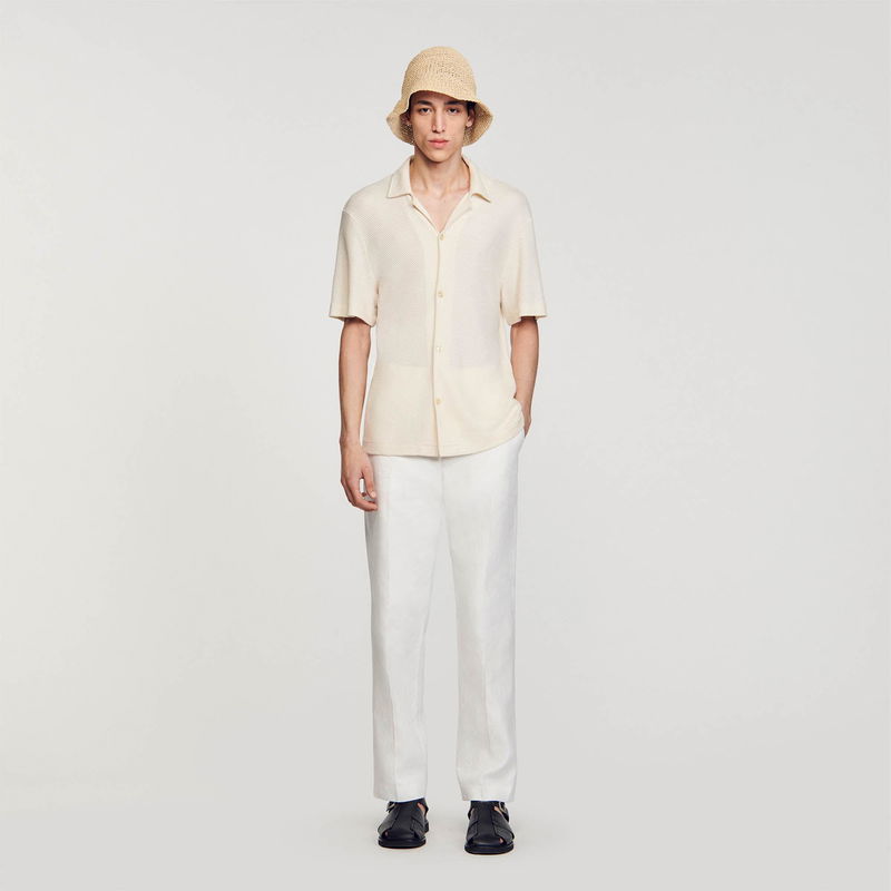 Sandro: Man wearing a cream-colored textured shirt and white trousers, with a straw hat.