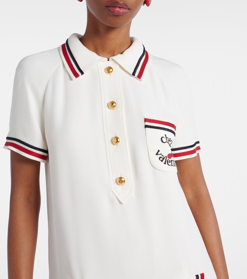 White polo shirt with gold buttons and red and white trim.