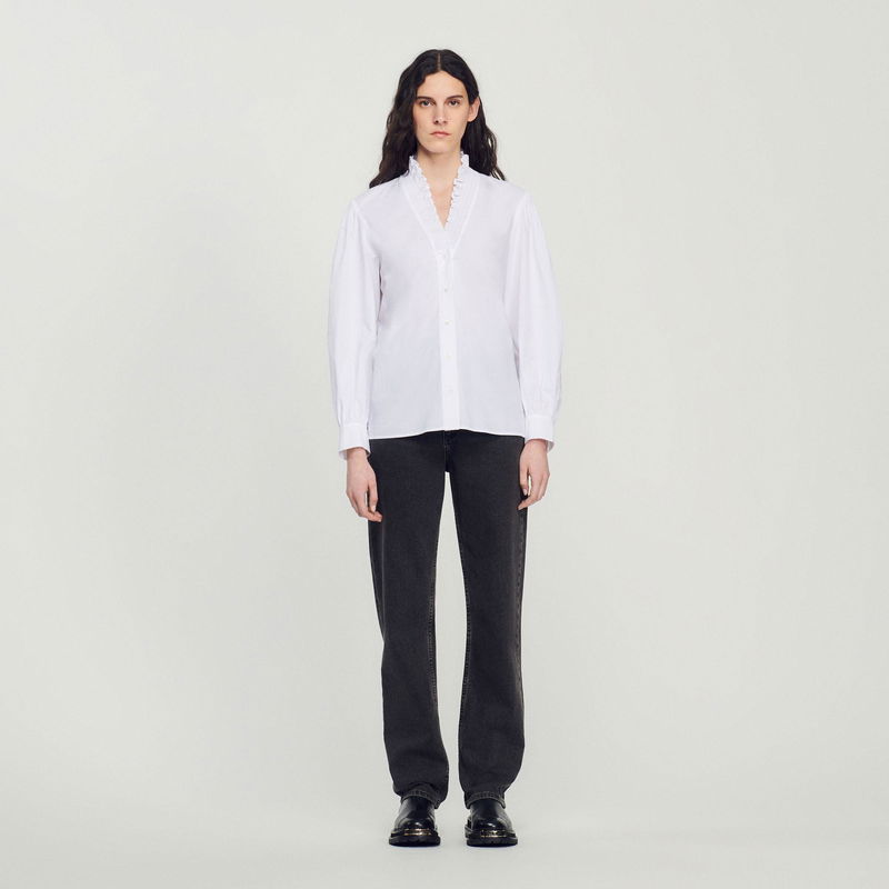 White ruffled blouse with model wearing black denim pants