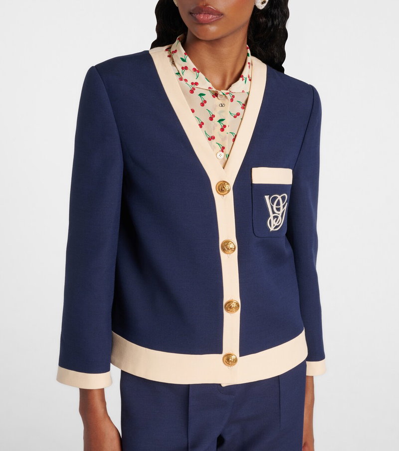 Navy blazer with cream trim and cherry embroidery, worn by a woman.