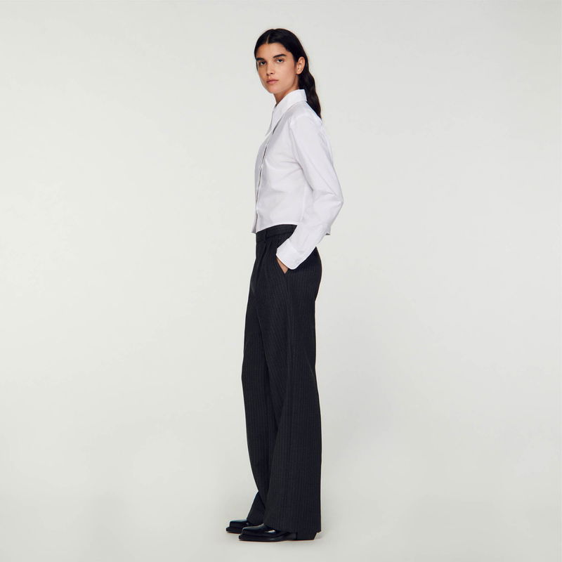 SANDRO - Woman in black and grey striped trousers and white shirt