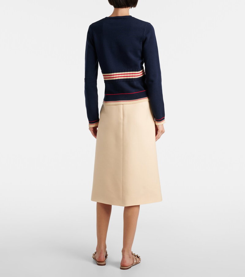 Valentino navy and red striped sweater with a beige pleated skirt.