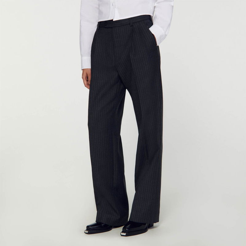 Dark pinstripe trousers worn by a model, with black shoes.
