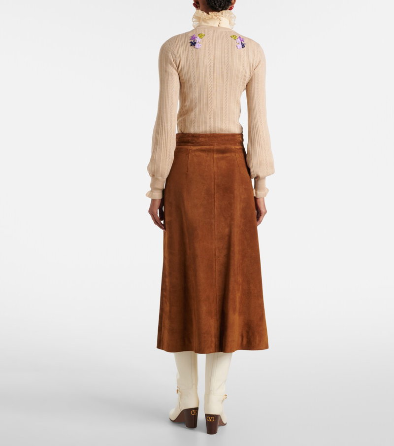 Valentino cream knit sweater with floral embroidery, paired with a brown suede midi skirt and white boots.