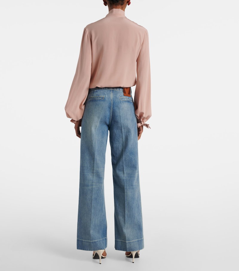 Pink silk blouse with puffed sleeves and wide-leg denim jeans.