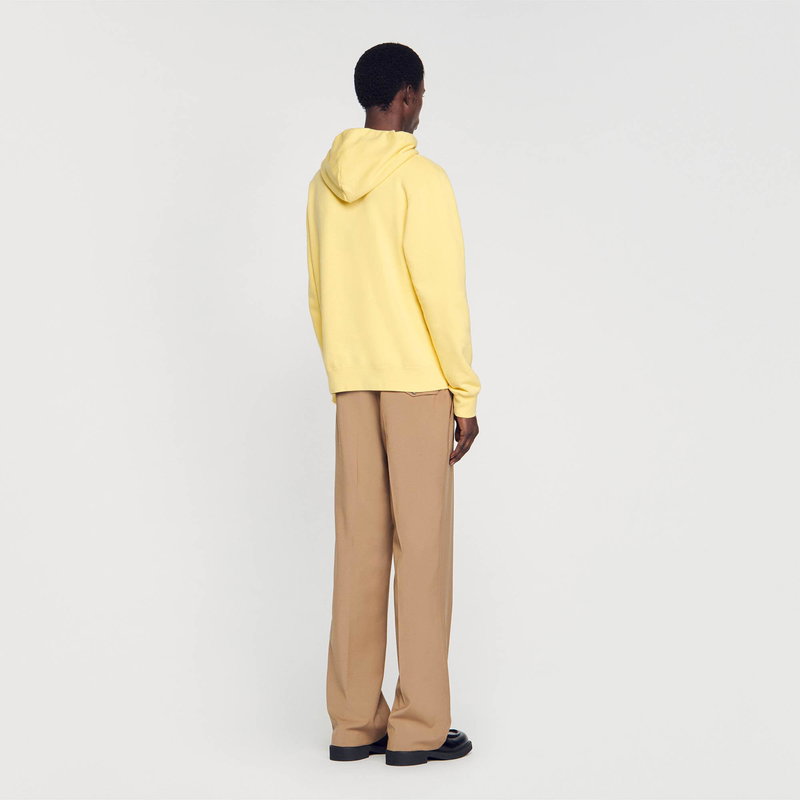 Yellow hoodie and tan trousers on a man.