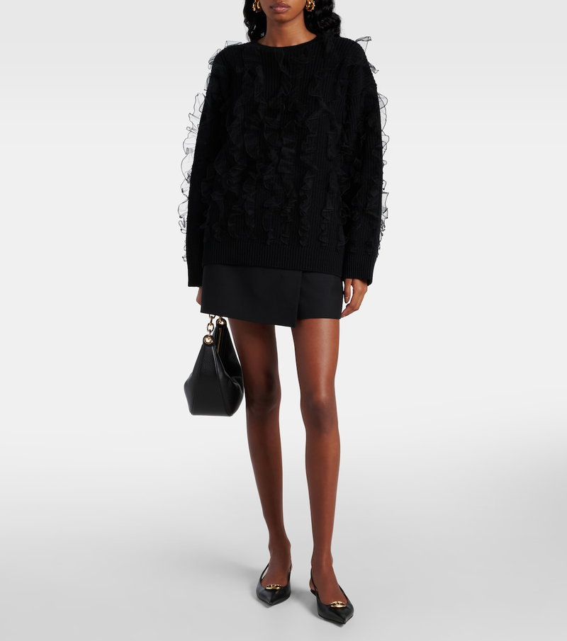 Black Valentino sweater with ruffled trim, paired with a skirt and heels.