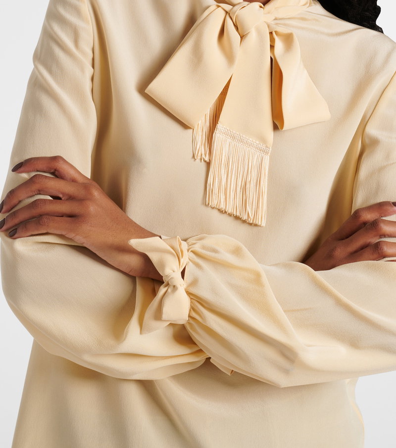 Cream silk blouse with a ruffled bow neckline.