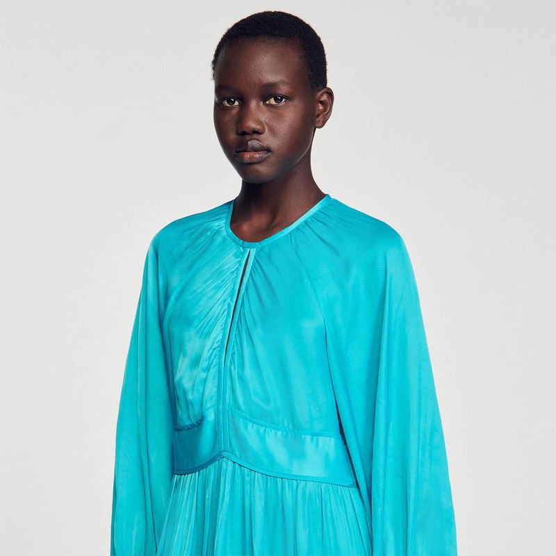 Satin turquoise dress with draped neckline, featuring a model.