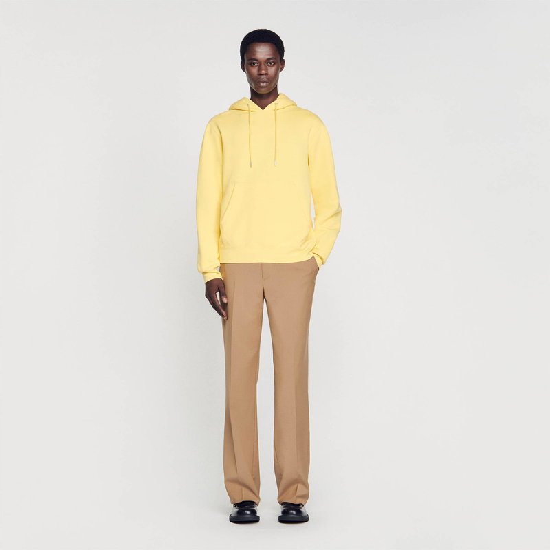 Man in a pale yellow hoodie and tan trousers.