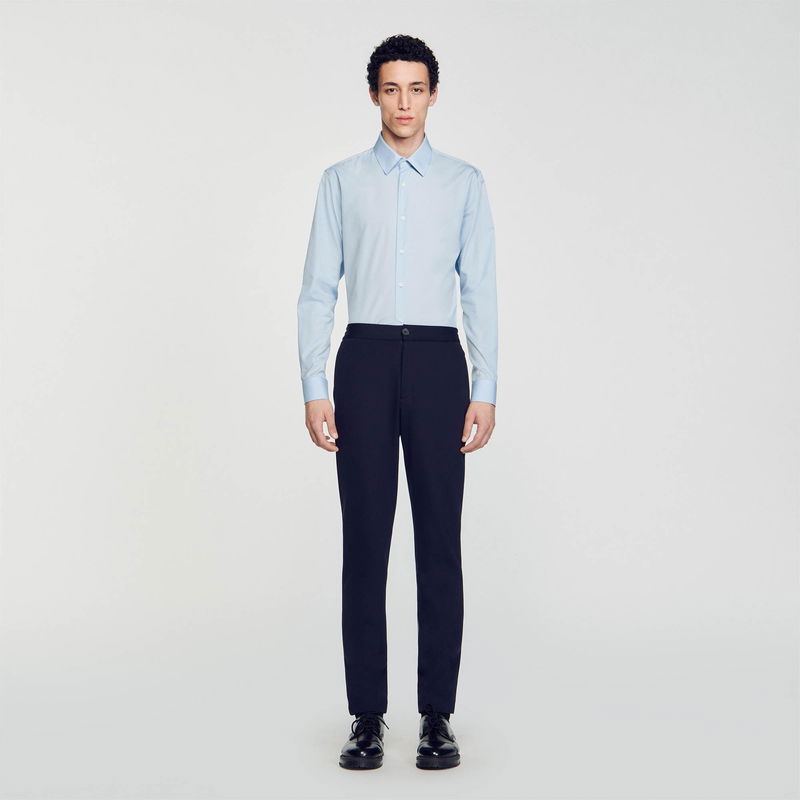Man in a light blue shirt and dark trousers.