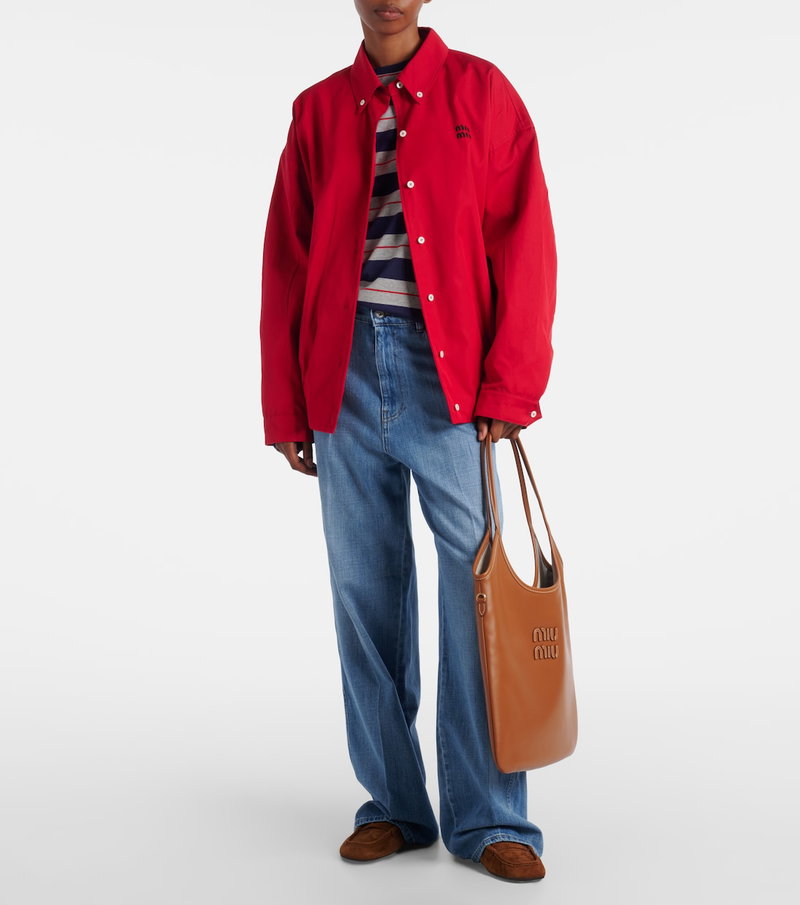 Red corduroy jacket with MIU MIU logo, model wearing denim jeans and tote bag.