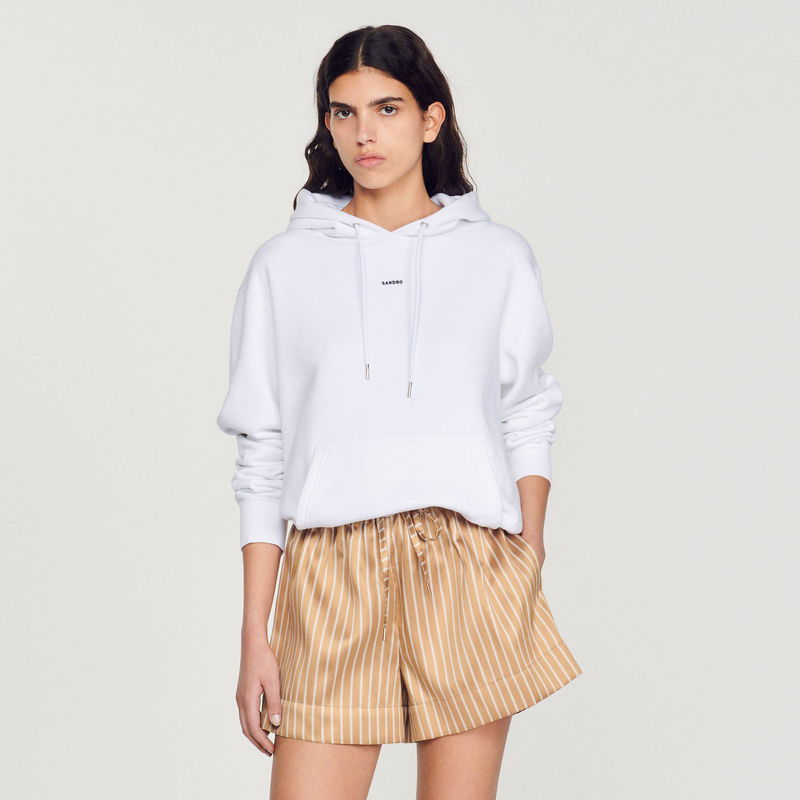 White SANDRO hoodie with a woman wearing it and matching shorts.