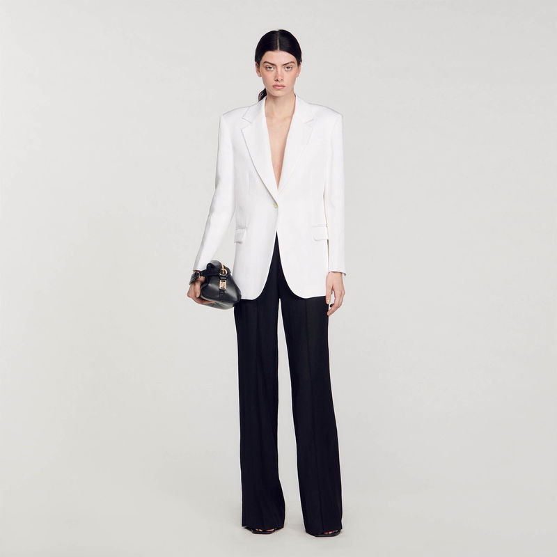 Sandro white blazer and black trousers with a small handbag.