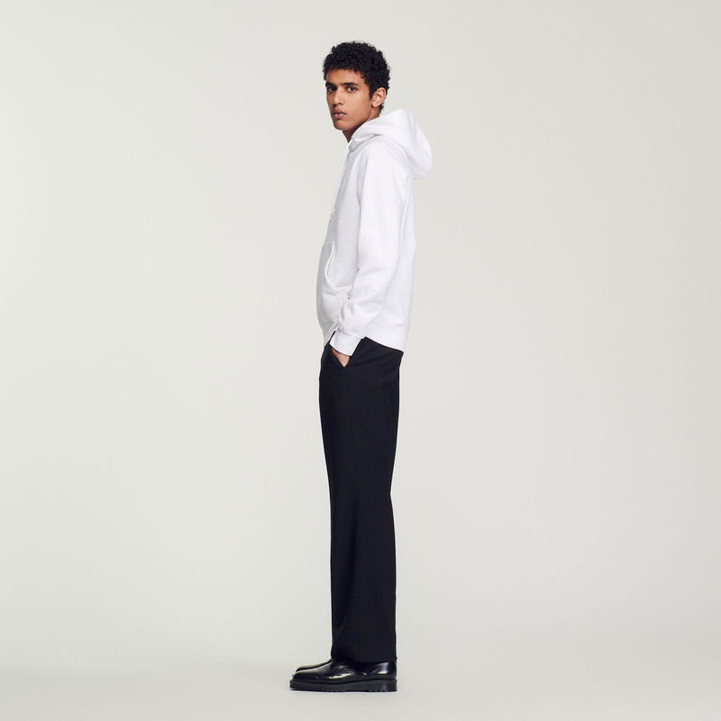 White hoodie and black trousers on a man.
